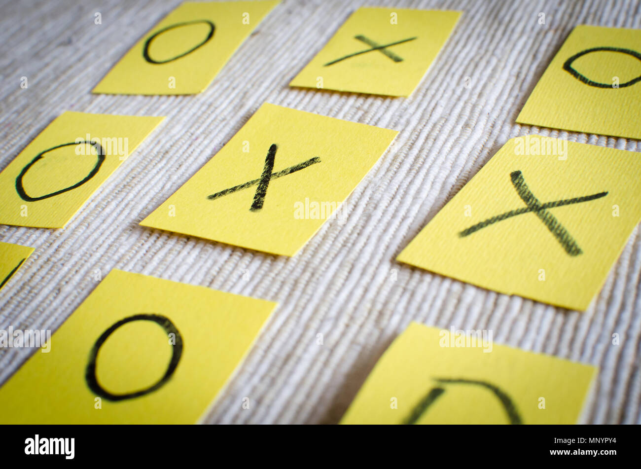 Tic Tac Toe Gioco , il vecchio classico gioco per due giocatori, lettere X e o su carta di colore giallo su sfondo a trama Foto Stock