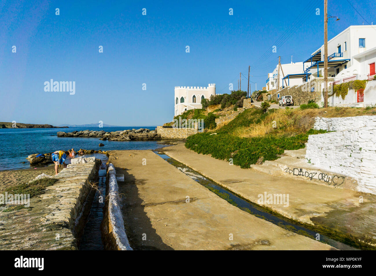 La gente di balneazione in primavera calda acqua nella spiaggia di Loutra (bagni)in kithnos. Minerali calde acque sorgive che scorrono attraverso un canale e si mescola con il mare Foto Stock