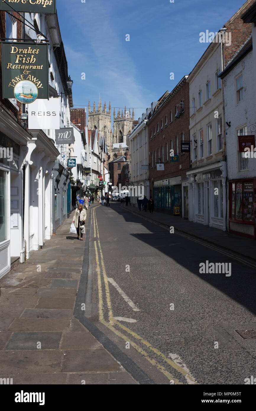 Bassa Petergate, York, Inghilterra. Una strada per lo shopping nella città di York, in Inghilterra con le torri della cattedrale di York Minster in background Foto Stock