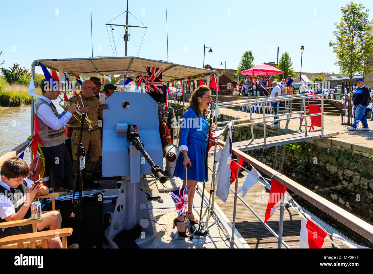 Saluto alla 40s popolare evento nostalgico. La vittoria di tempo di guerra Band eseguendo sulla coperta della barca, con la donna adulta cantando e sventola bandiera dell'Union Jack. Foto Stock