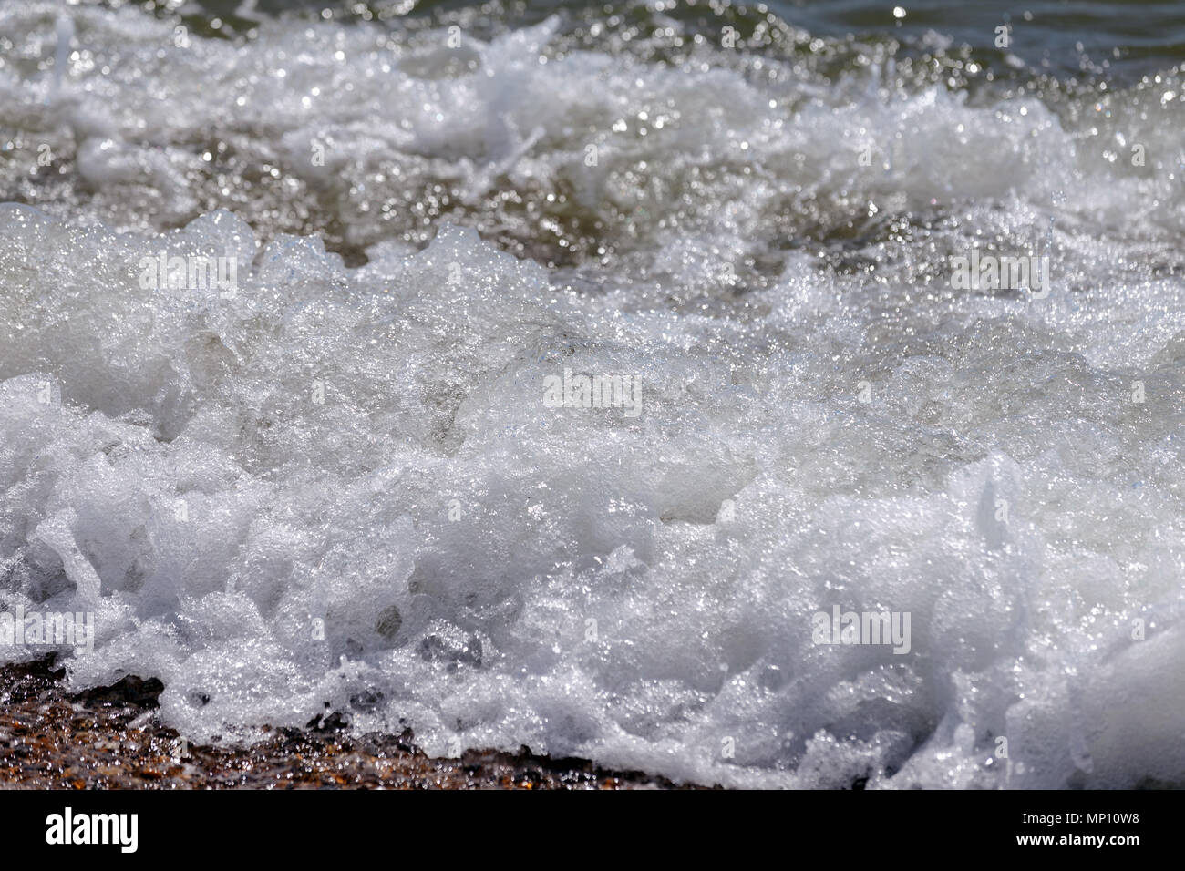 Le onde del mare lo sbarco sulla costa di una spiaggia di ciottoli nel Regno Unito. Foto Stock