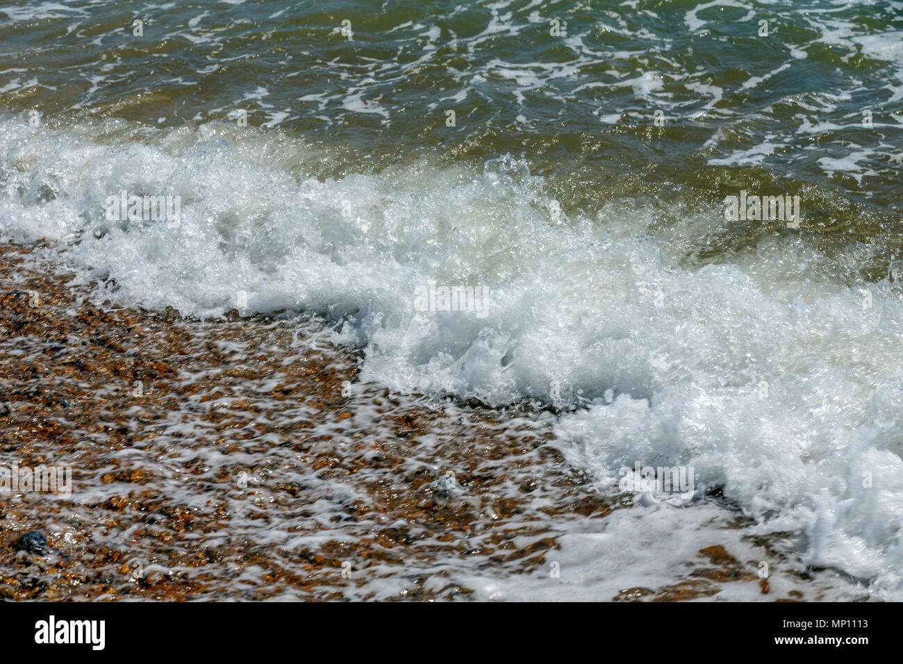 Le onde del mare lo sbarco sulla costa di una spiaggia di ciottoli nel Regno Unito. Foto Stock