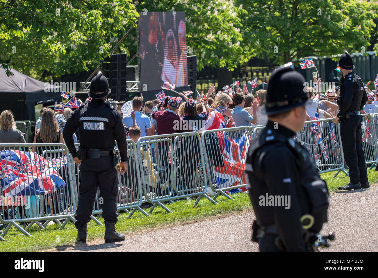 19 Maggio 2018 - i funzionari di polizia a sorvegliare la lunga passeggiata in Windsor guarda il livestream delle nozze reali del principe Harry e Meghan Markle su giganteschi schermi tv a fianco di fan. Foto Stock