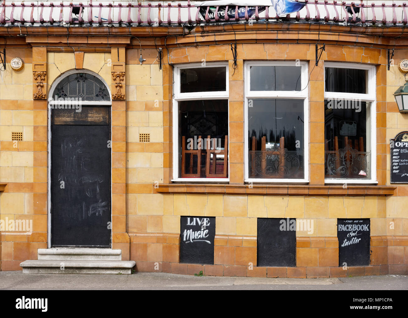 La porta sbarrata e sedie sulle tavole di un chiuso pub Foto Stock