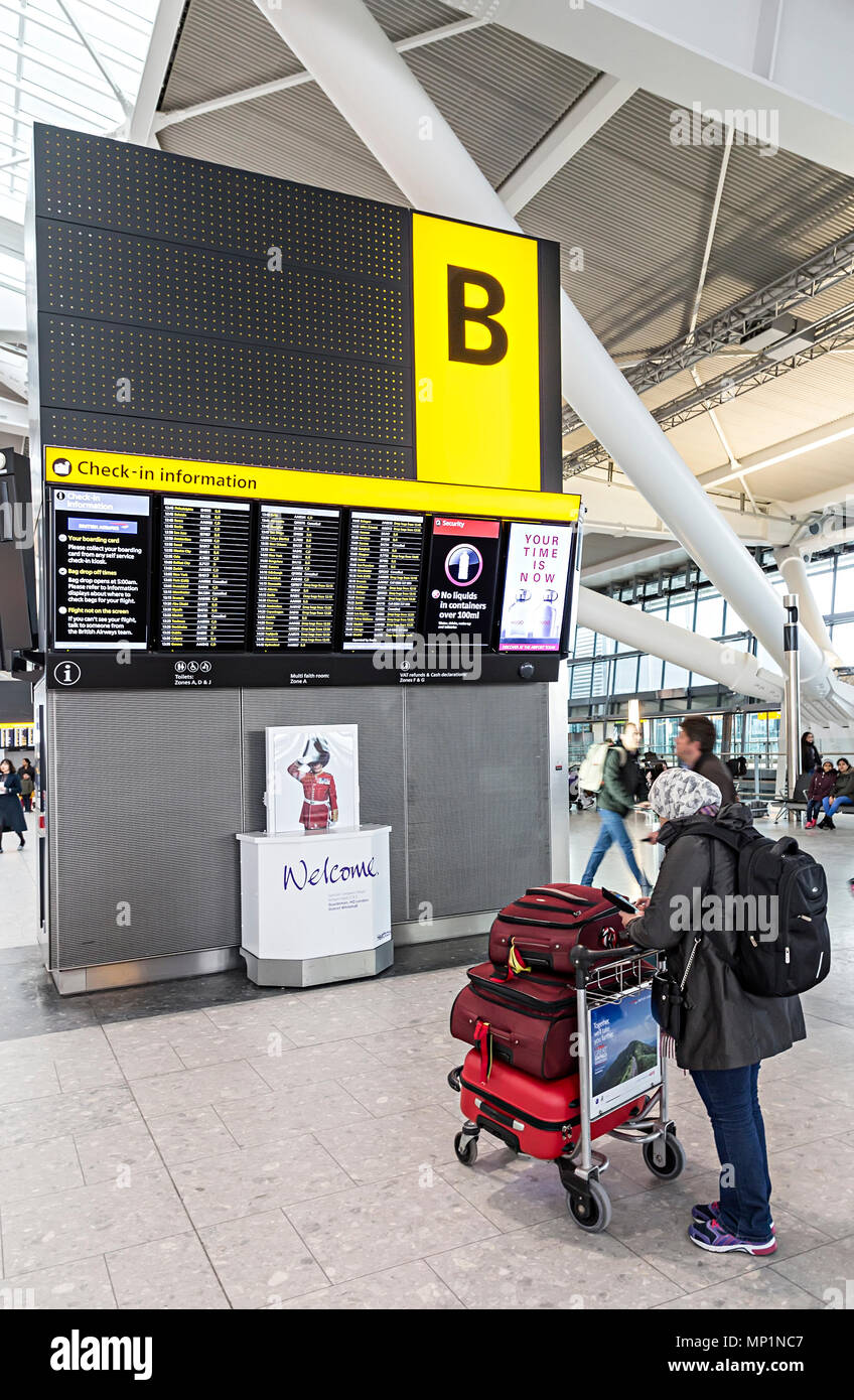 Le persone che ricercano informazioni di volo bordo, l'aeroporto di Heathrow di Londra, Regno Unito Foto Stock