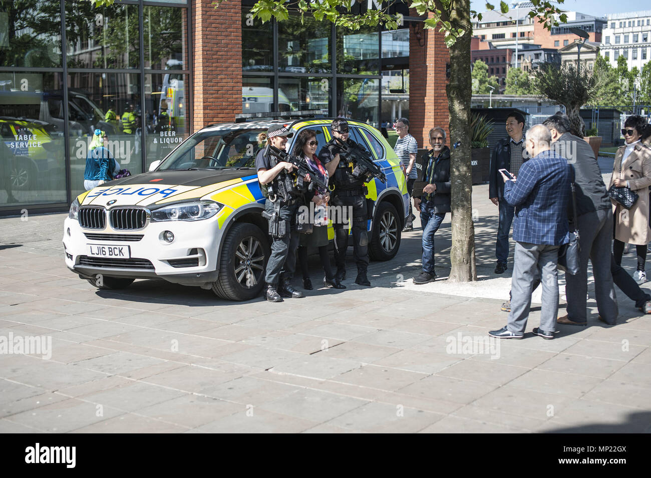 Manchester, Greater Manchester, UK. 19 Maggio, 2018. I turisti pongono per le immagini sui Piccadilly Gardens nel Manchester con poliziotti armati davanti al rally FLA e UAF rally e marzo. Uniti contro il razzismo protesta contro la Football Lads associazione al Rally di Castlefield Arena di Manchester a quasi un anno dopo il Manchester Arena bomba. Credito: Steven velocità SOPA/images/ZUMA filo/Alamy Live News Foto Stock