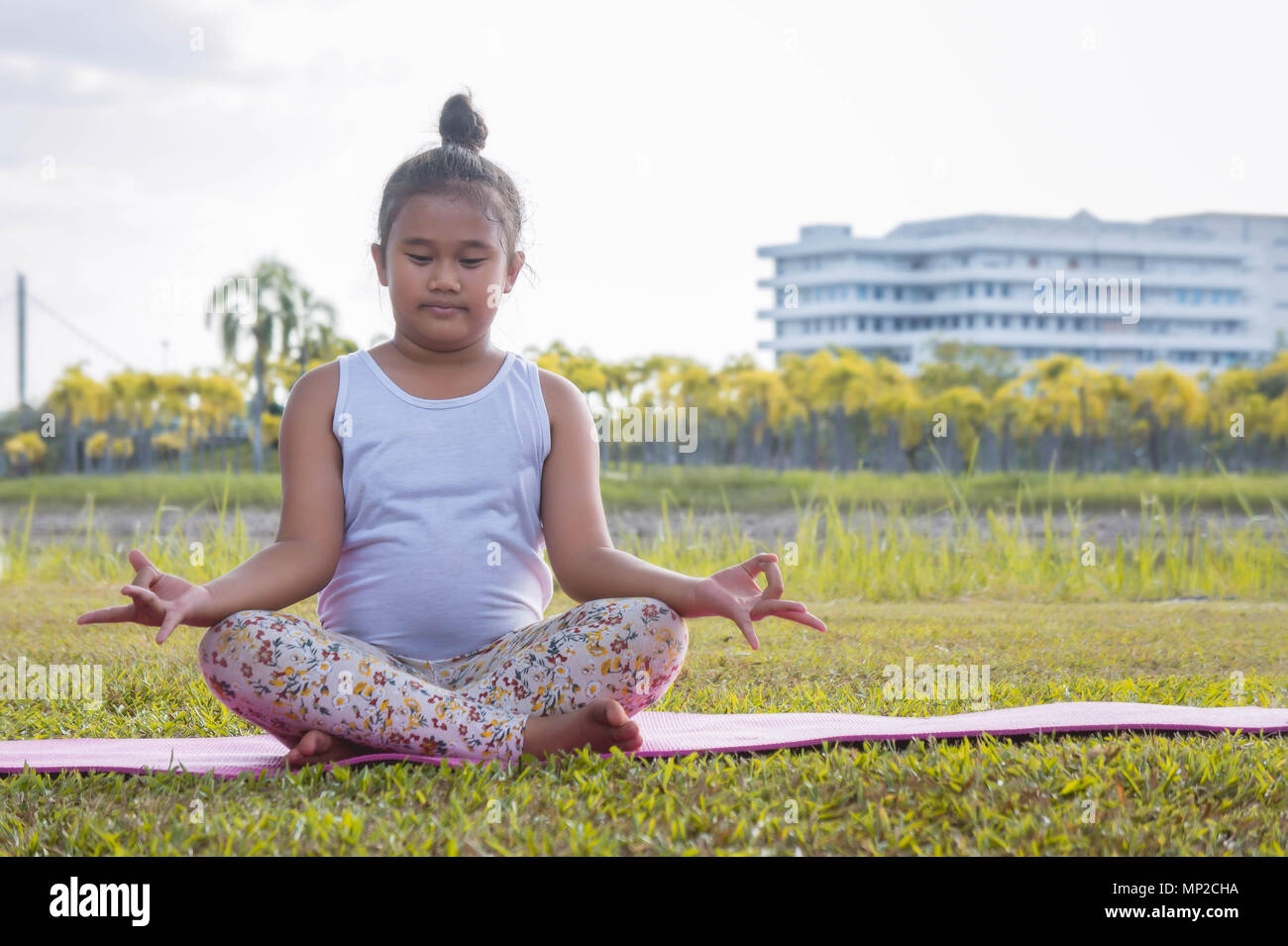 La ragazza la pratica dello yoga nel parco rafforza la concentrazione e la salute , Yoga per bambini divertirsi la meditazione delle attività per i bambini Foto Stock