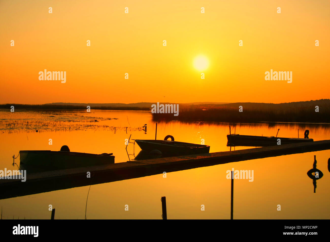 Vista tramonto da una piccola dock con il legno vecchio di barche da pesca e reed nella distanza. Serenità. Foto Stock