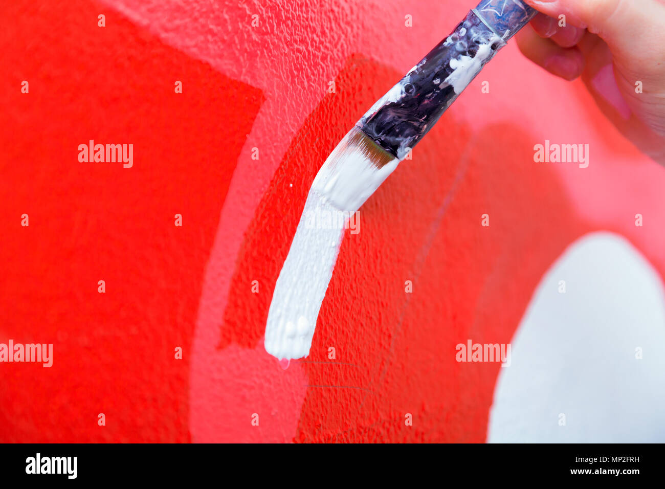 Giovane donna pittore e madre boy disegna per un bambino su un muro bianco un bel rosso auto in una luce stanza dei bambini Foto Stock