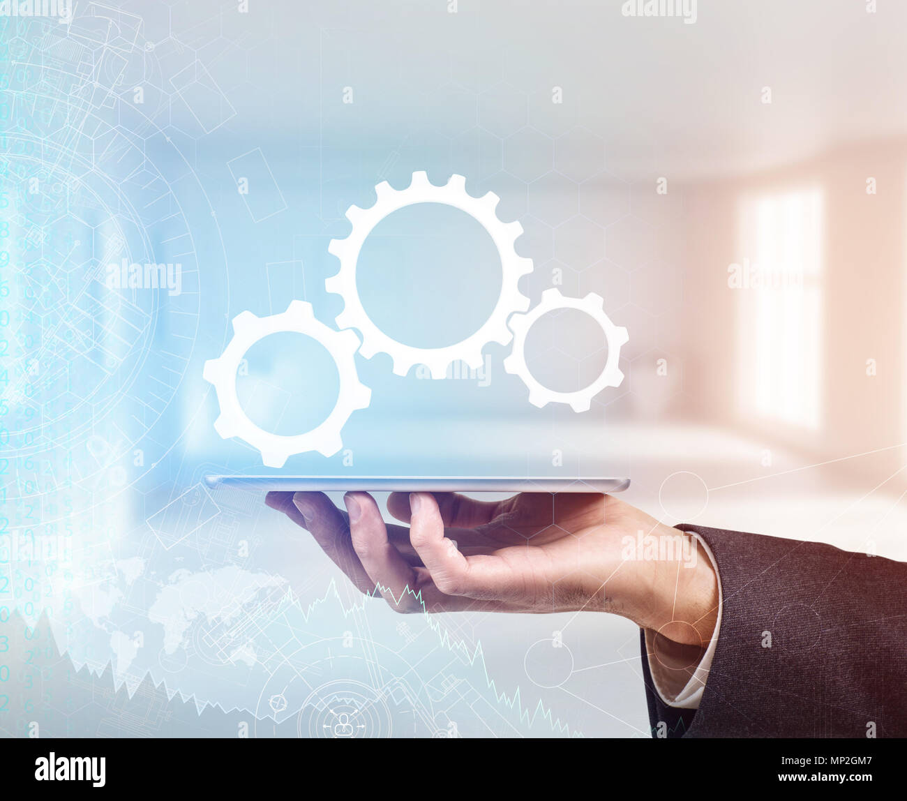 In mano una tuta detiene una rutilante tablet con ingranaggi metallici. Foto Stock