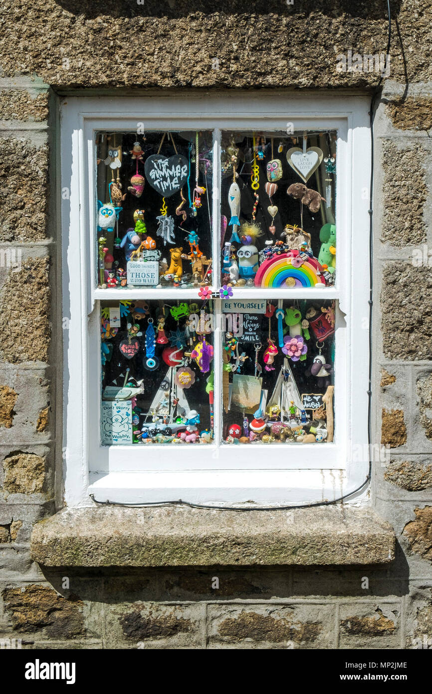 Colouful giocattoli e novità appesi in una finestra in un cottage. Foto Stock