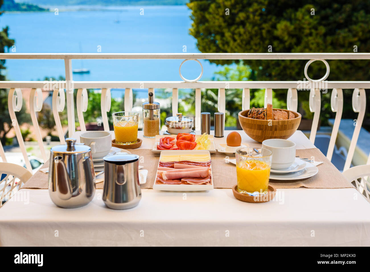 Continentale colazione di mattina messa in tavola con vista mare è servita. Hotel Ristorante prima colazione a buffet è servita su un terrazzo in prossimità dell'oceano. Vacanza Foto Stock