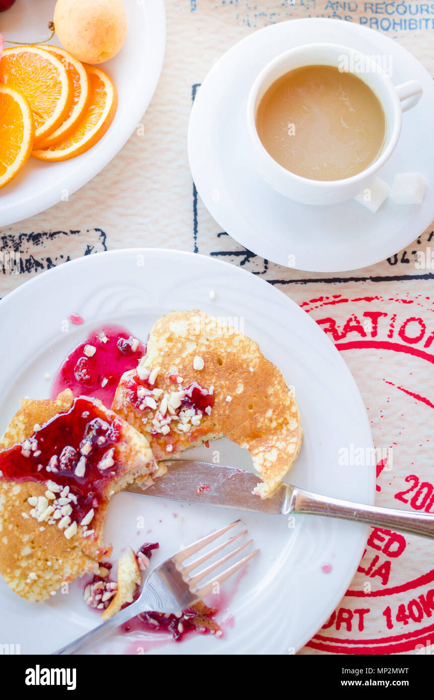 Prima colazione inclusa classic pancake con confettura di lamponi, caffè con latte e frutta. Buona mattina. Vista dall'alto. Foto Stock
