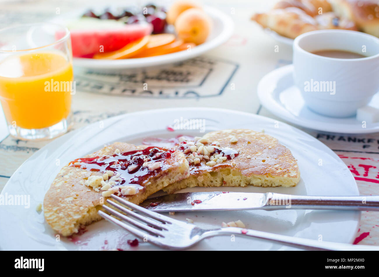 Prima colazione inclusa classic pancake con confettura di lamponi, caffè con latte, frutta e dolci. Buona mattina. Messa a fuoco selettiva. Foto Stock