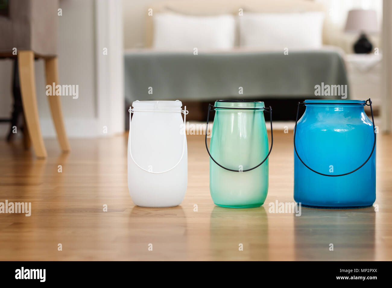 Tre vasi di vetro con diverse dimensioni e colori su un pavimento di legno, arredamento sfondo. Foto Stock