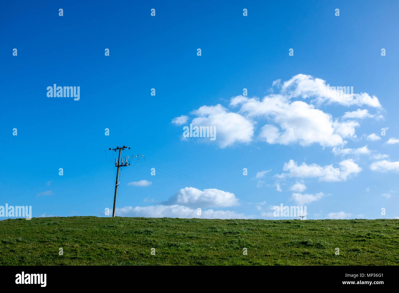 Le linee di alimentazione in terreni agricoli con profondo cielo blu e soffici nuvole nel Cheshire Regno Unito Foto Stock