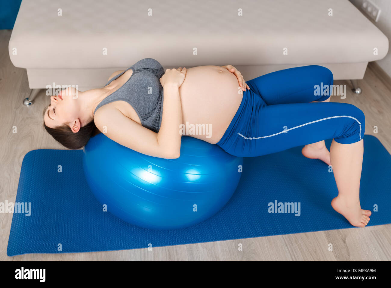 Donna incinta facendo esercizio di rilassamento a montare la sfera a casa Foto Stock