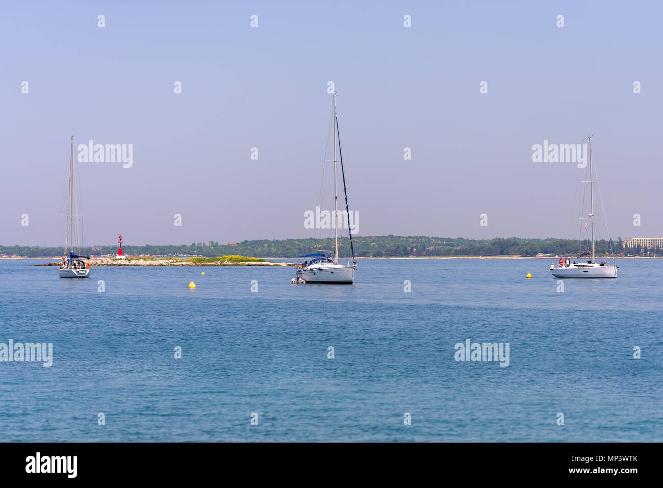 Yacht ancorati nella baia, barche a vela, una piccola isola con faro rosso in background Foto Stock