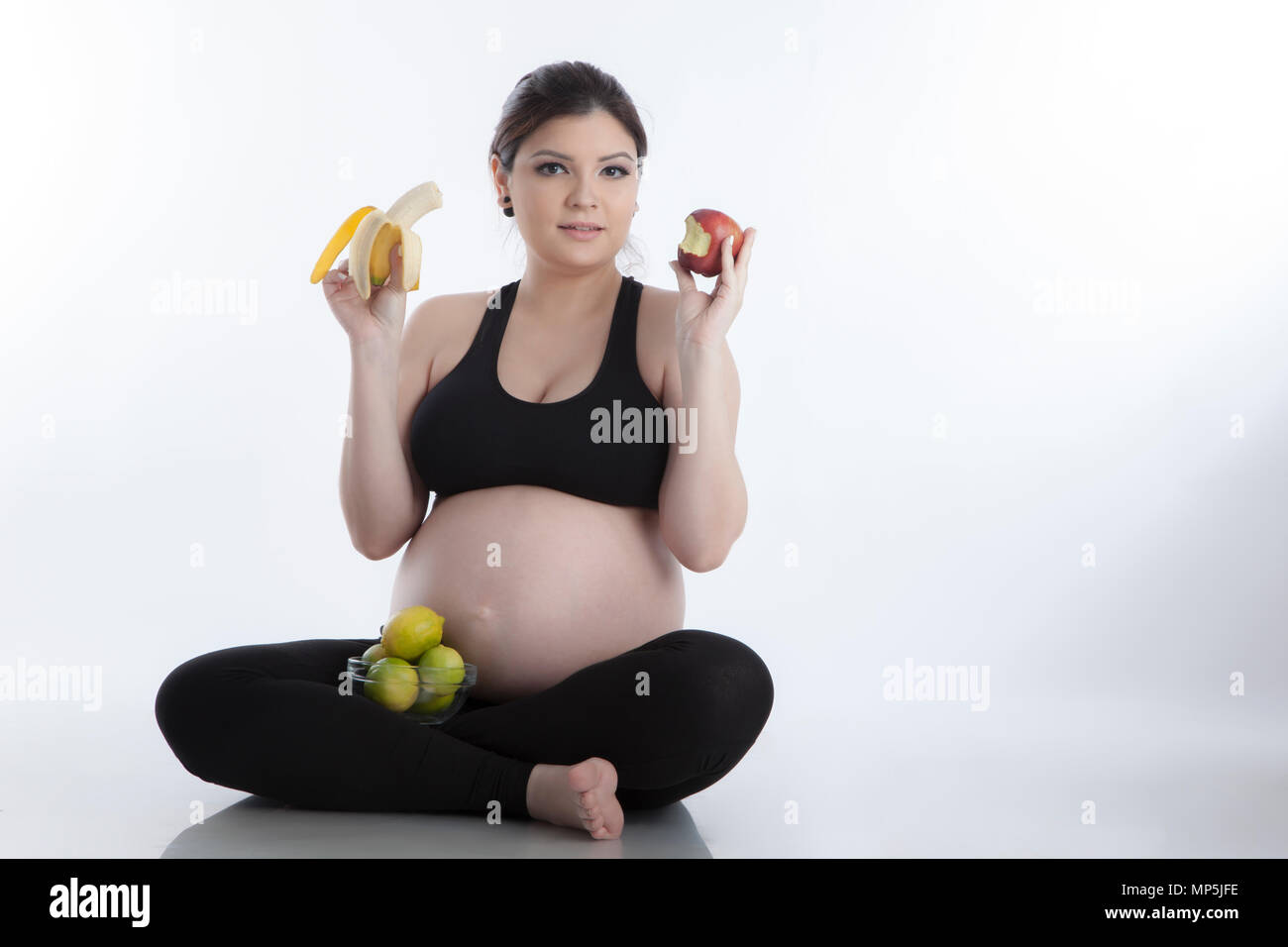 Un sano donna incinta di mangiare la vitamina ricchi frutti su sfondo bianco Foto Stock