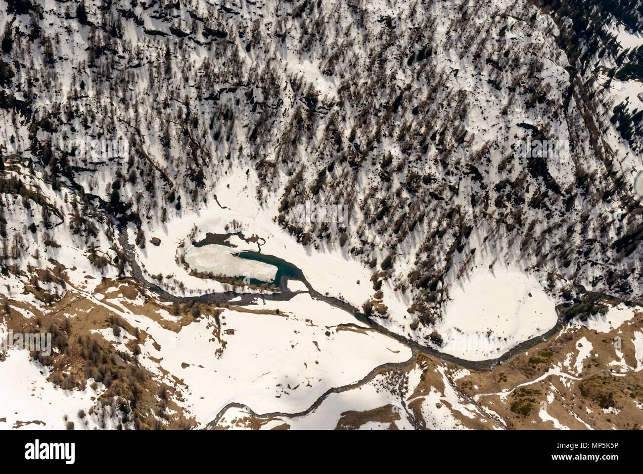 Riprese aeree, da un piccolo aereo, del fiume che scorre tra innevati boschi di abete , girato in Alta Valle Brembana in primavera brillante luce, Orobie, Bergamo , Ita Foto Stock