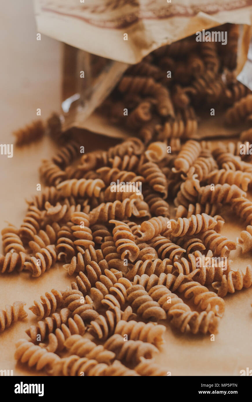 Pasta integrale fusilli da tutto organico farro grano cadendo da un sacchetto di carta Foto Stock