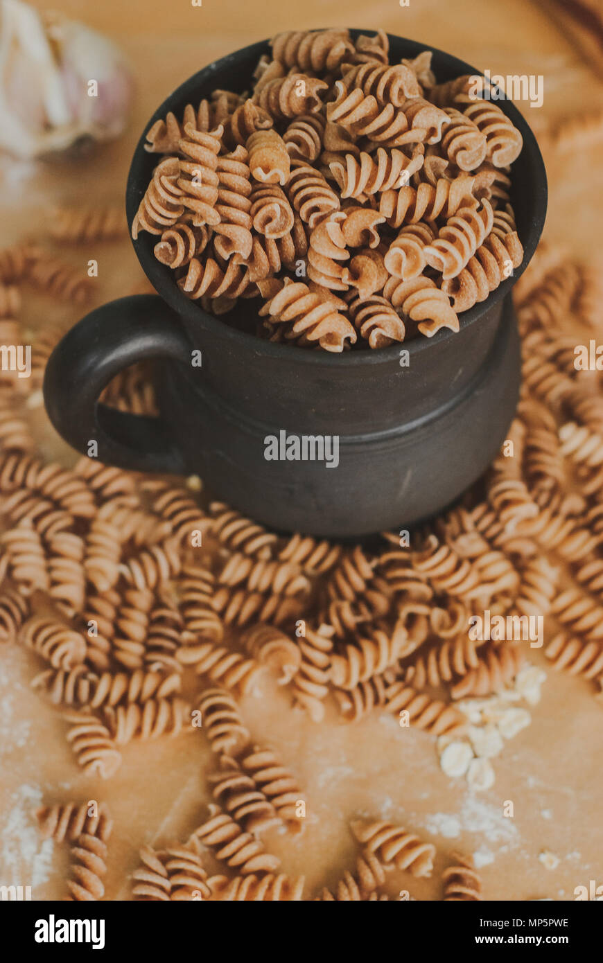 Pasta integrale di farro biologico la caduta di una tazza nera su una carta artigianale Foto Stock