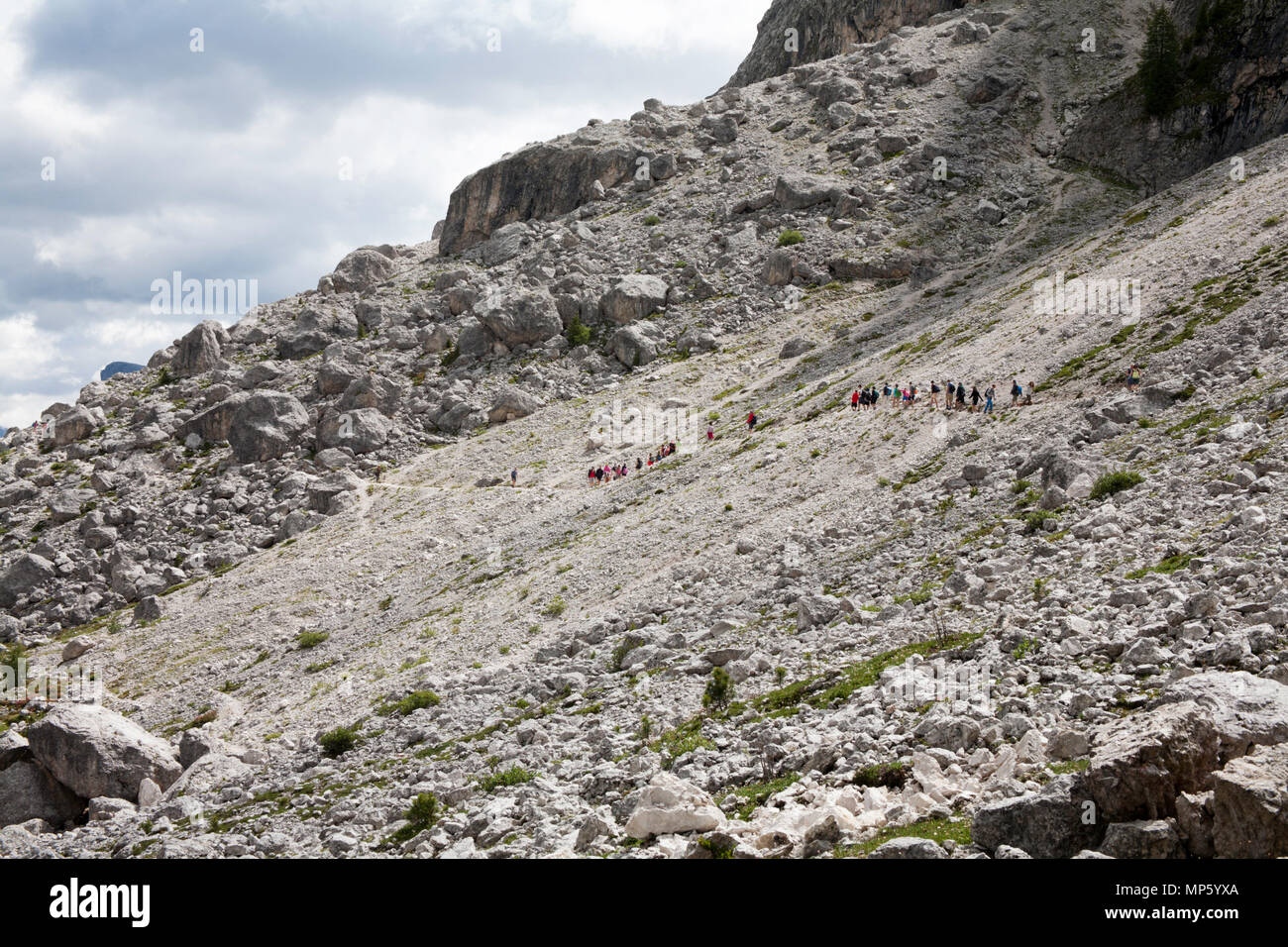 Un gruppo di trekking che attraversa un percorso roccioso il sentiero 526A sotto le scogliere del Sassolungo al Piz Sella al di sopra di Selva di Val Gardena Dolomiti Italia Foto Stock