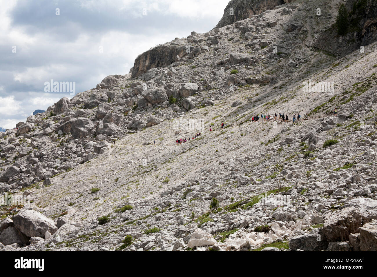 Un gruppo di trekking che attraversa un percorso roccioso il sentiero 526A sotto le scogliere del Sassolungo al Piz Sella al di sopra di Selva di Val Gardena Dolomiti Italia Foto Stock