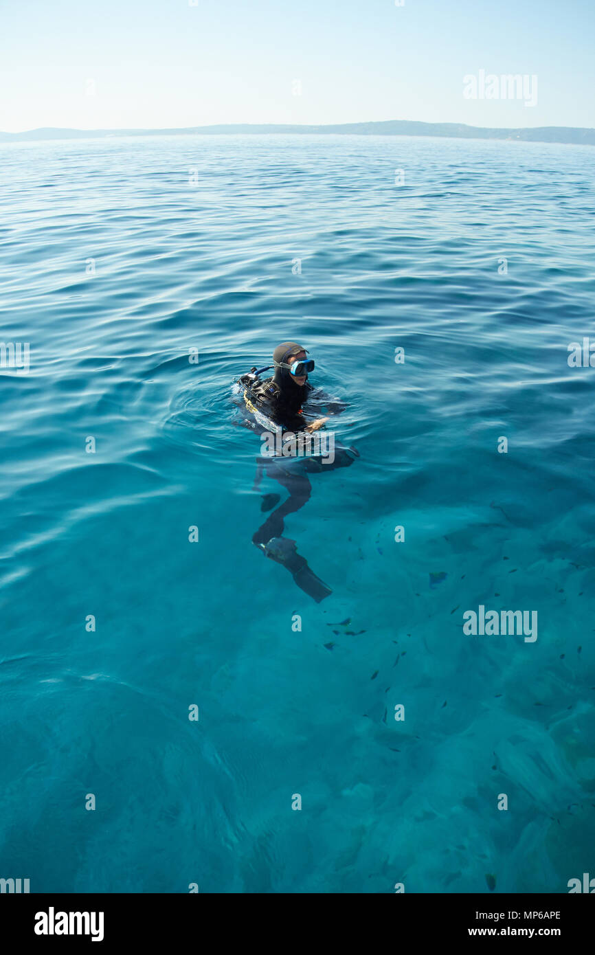 Scuba Diver sulla superficie del mare Adriatico in Croazia. Colpo lungo. Orizzonte su acqua. Foto Stock