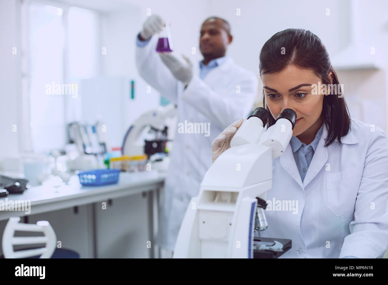 Ricercatore confermato guardando al microscopio Foto Stock