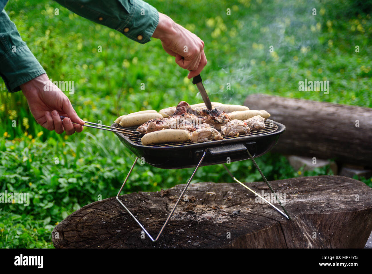 Man mano la cottura griglia per il barbecue su grillware portatile Foto  stock - Alamy