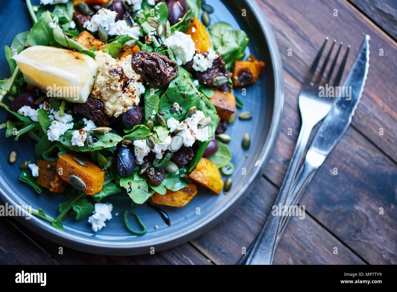 Deliziosa insalata seduta con posate su una tavola in legno rustico Foto Stock