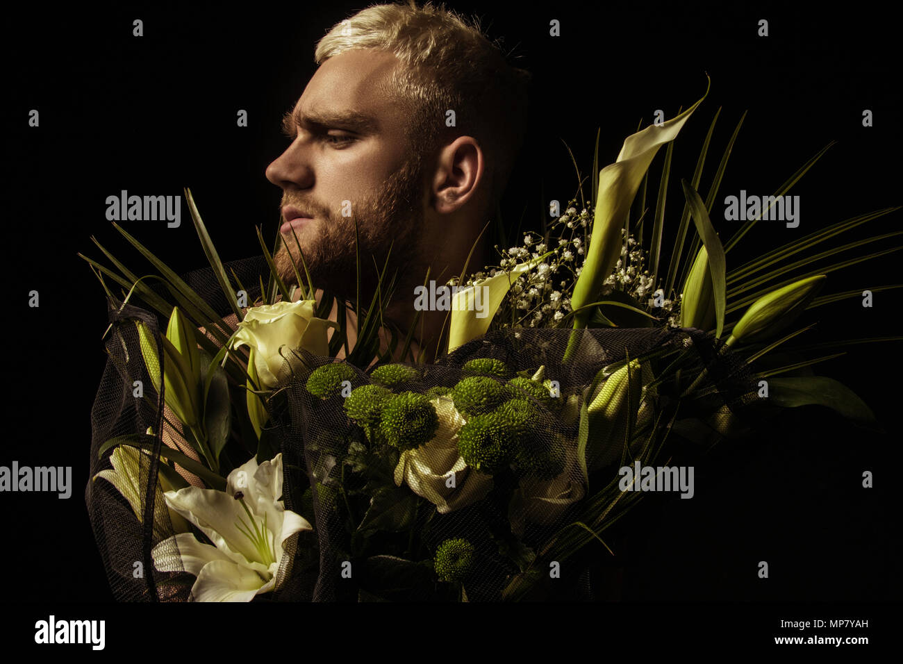 Elegante uomo bianco con bouquet di fiori su sfondo nero Foto Stock
