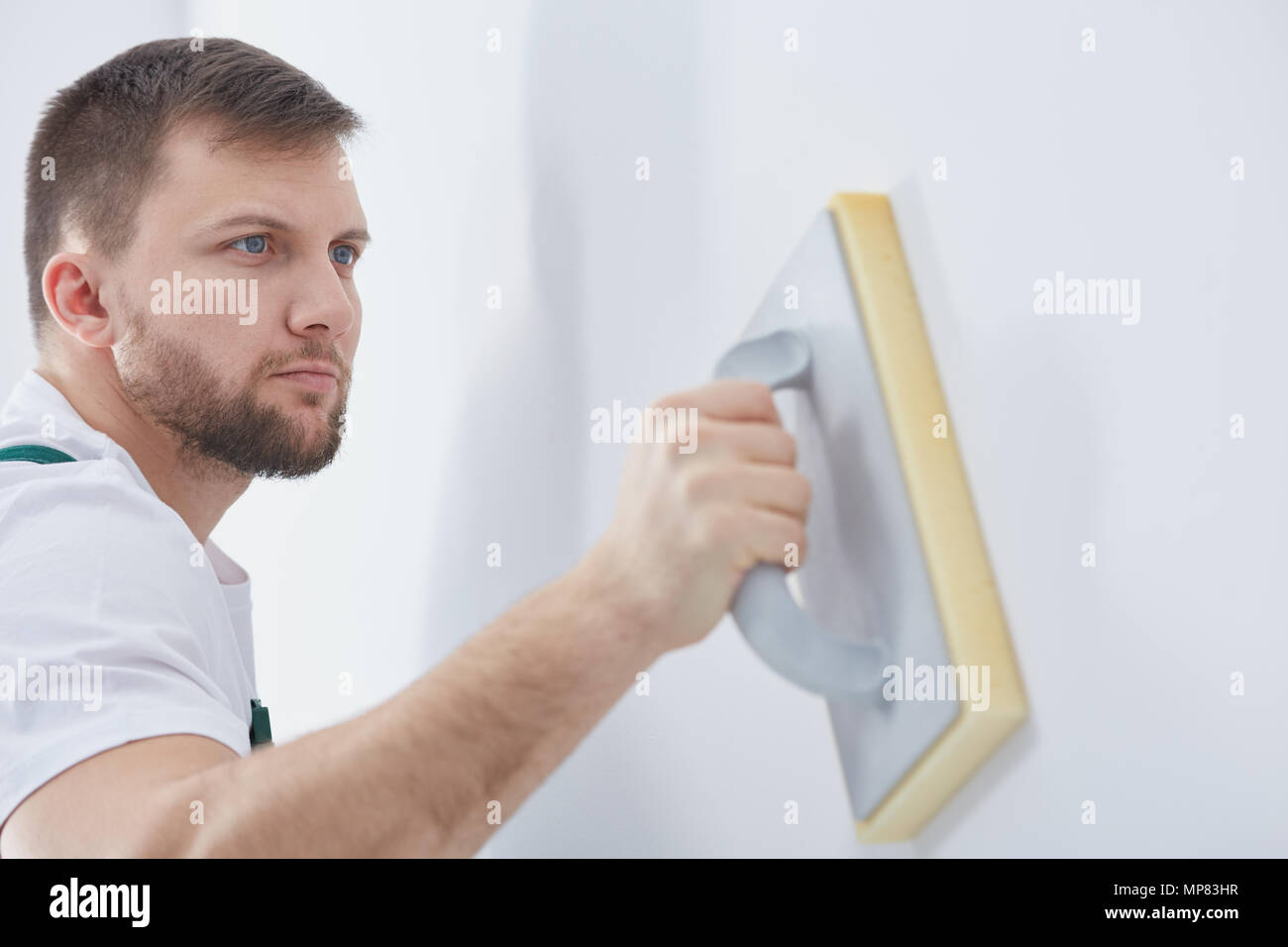 Specialista di giovani sfregamento lungo la parete prima della verniciatura Foto Stock