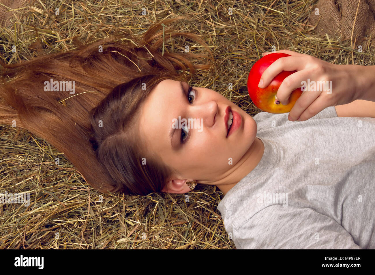 Bella Donna sorridente con molti apple nel cesto su pagliaio presso l'azienda Foto Stock