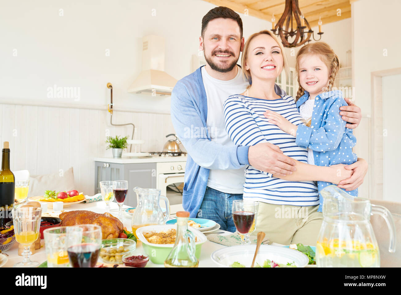 Il successo di giovani famiglie che pongono al tavolo per la cena Foto Stock