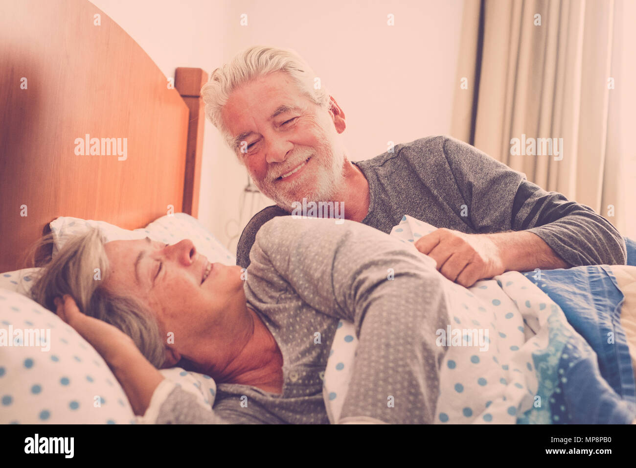 Paio di senior persone sposate riposo a letto, godendo di svegliarsi con un sorriso. Felice pensionato uomo caucasico e donna Foto Stock