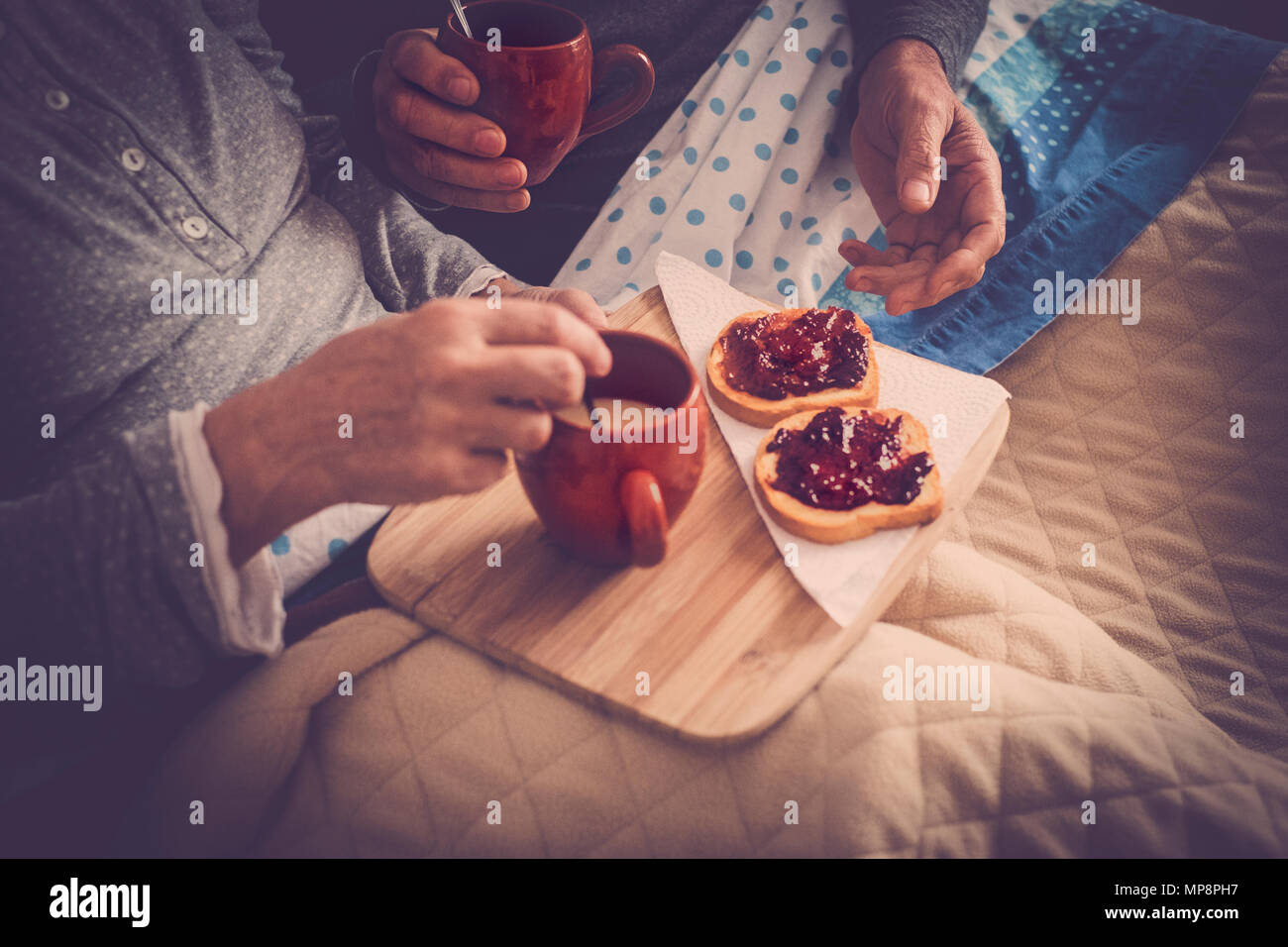 Paio di senior persone sposate riposo a letto, gustando la prima colazione e una tazza di tè o caffè. Felice pensionato uomo caucasico e donna Foto Stock