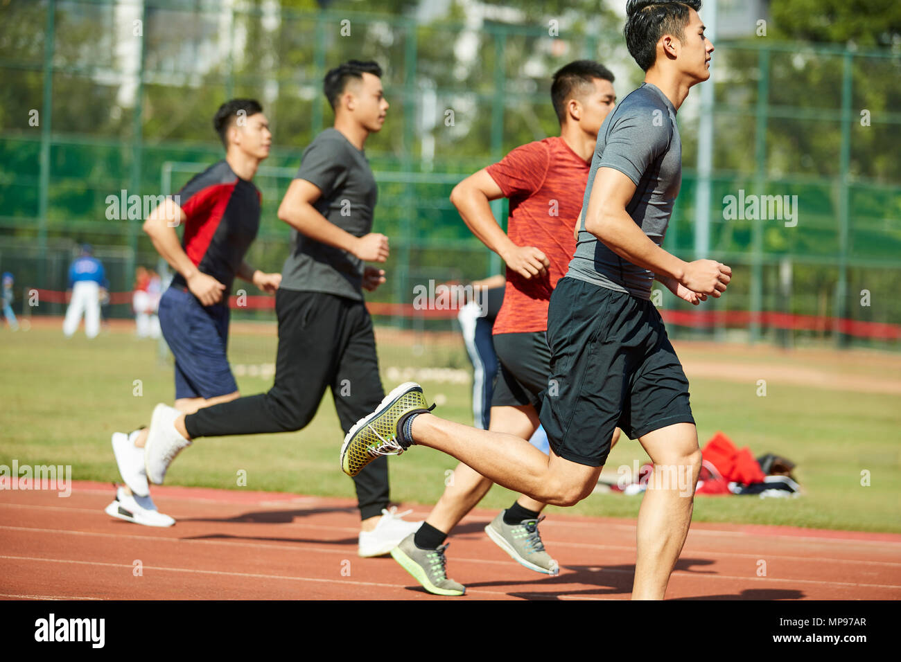 Giovani asiatici atleti adulti formazione in esecuzione sulla via, vista laterale. Foto Stock