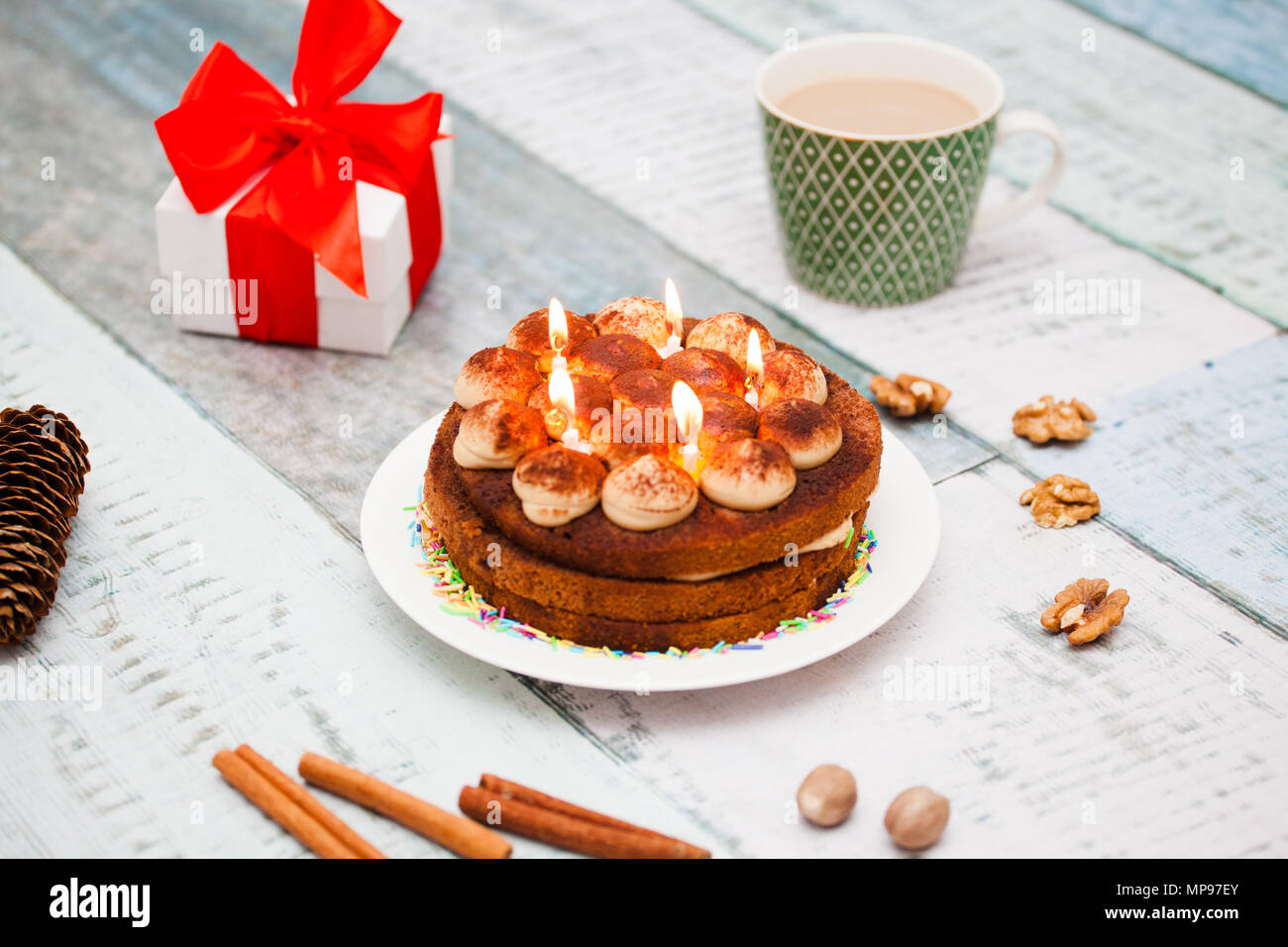 Una torta con cinque candele su una tavola di legno, una tazza e un regalo Foto Stock