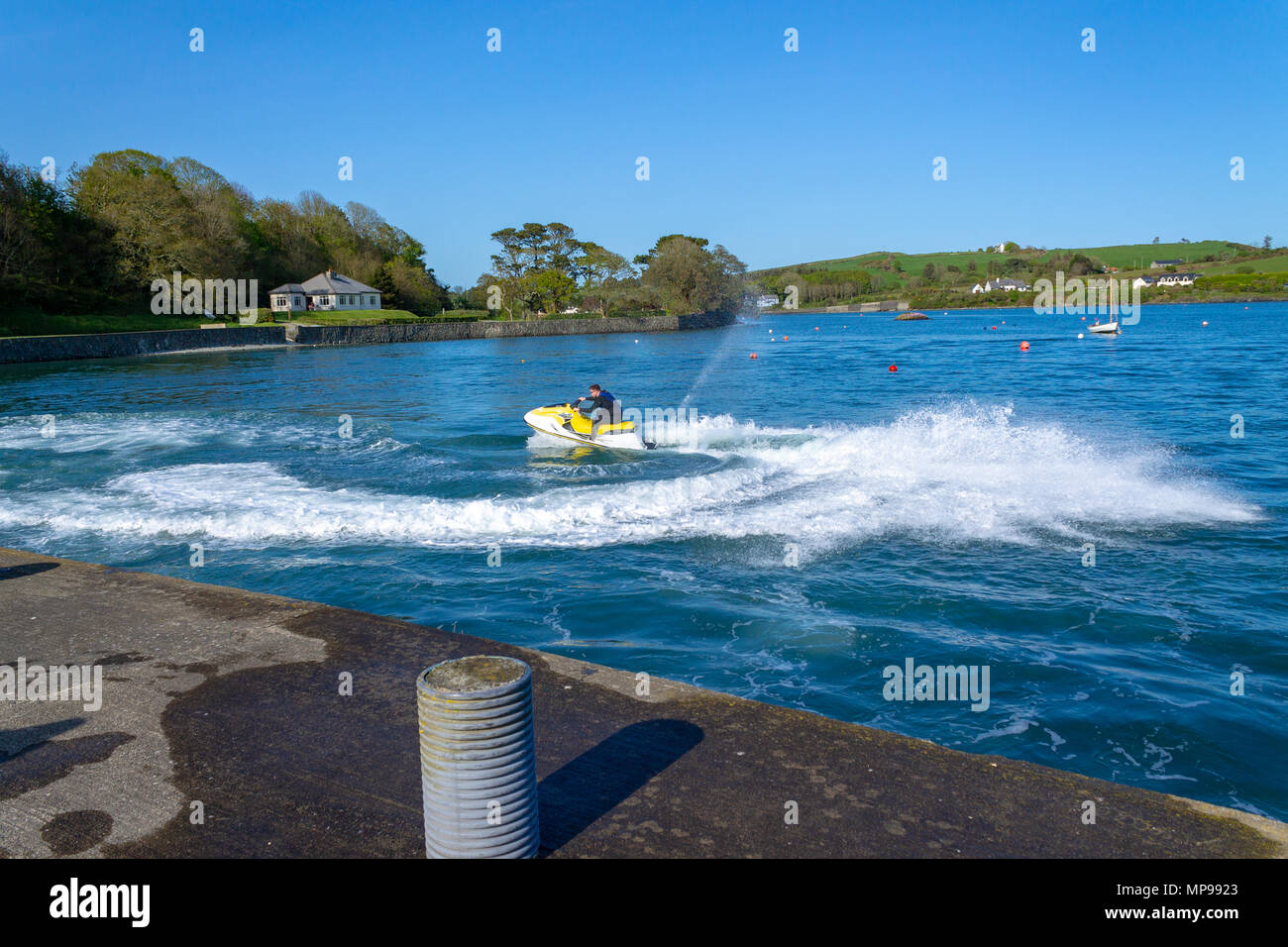 Giovane maschio a cavallo di un jet ski su una serata estati in porto castletownshend, Irlanda. Foto Stock