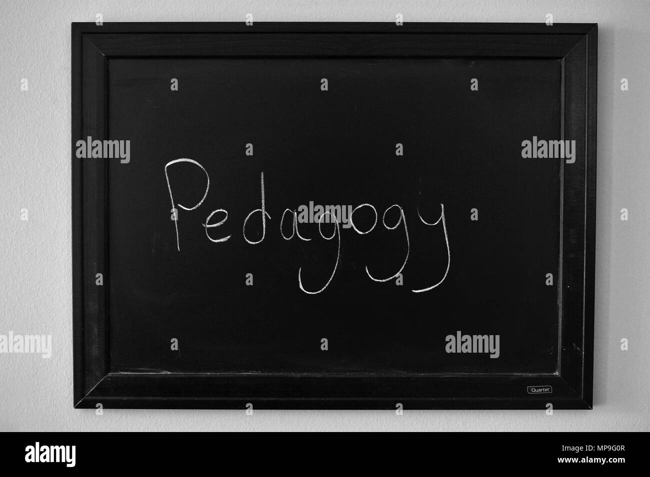 Pedagogia scritto in bianco gesso su una parete montata Blackboard. Foto Stock