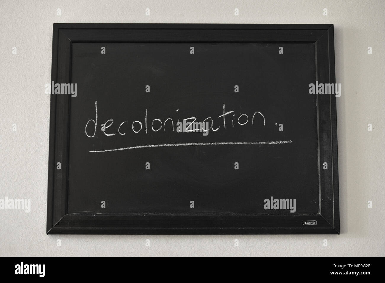 Decolonizzazione scritto in bianco gesso su una parete montata Blackboard. Foto Stock
