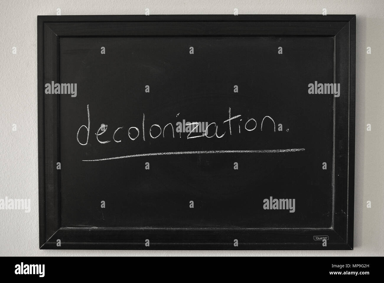 Decolonizzazione scritto in bianco gesso su una parete montata Blackboard. Foto Stock
