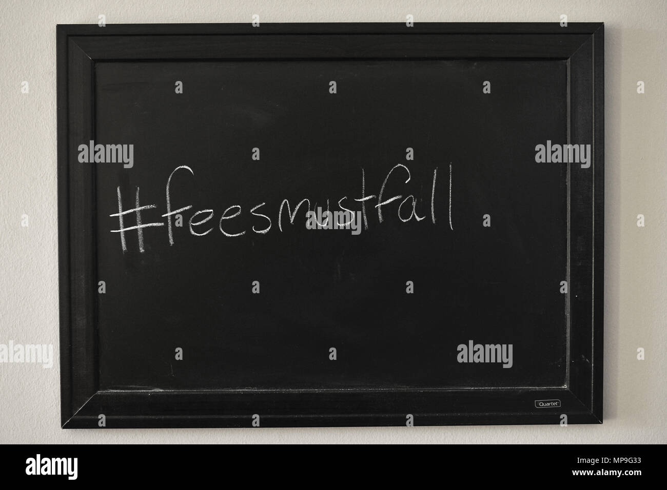 #Feesmustfall scritto in bianco gesso su una parete montata Blackboard. Foto Stock