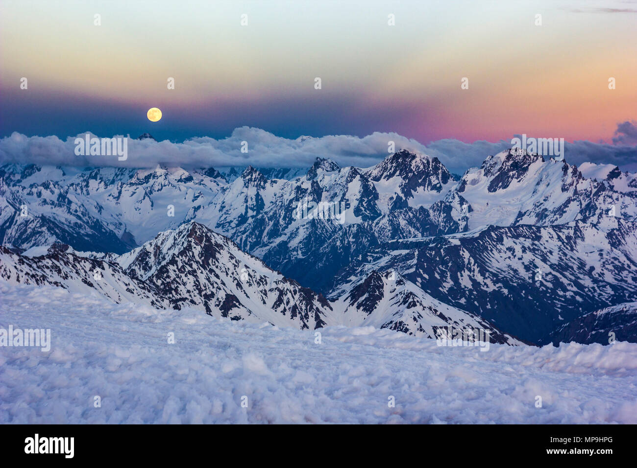 Innevate montagne del Caucaso al tramonto con moonrising e raggi Anticrepuscular Foto Stock