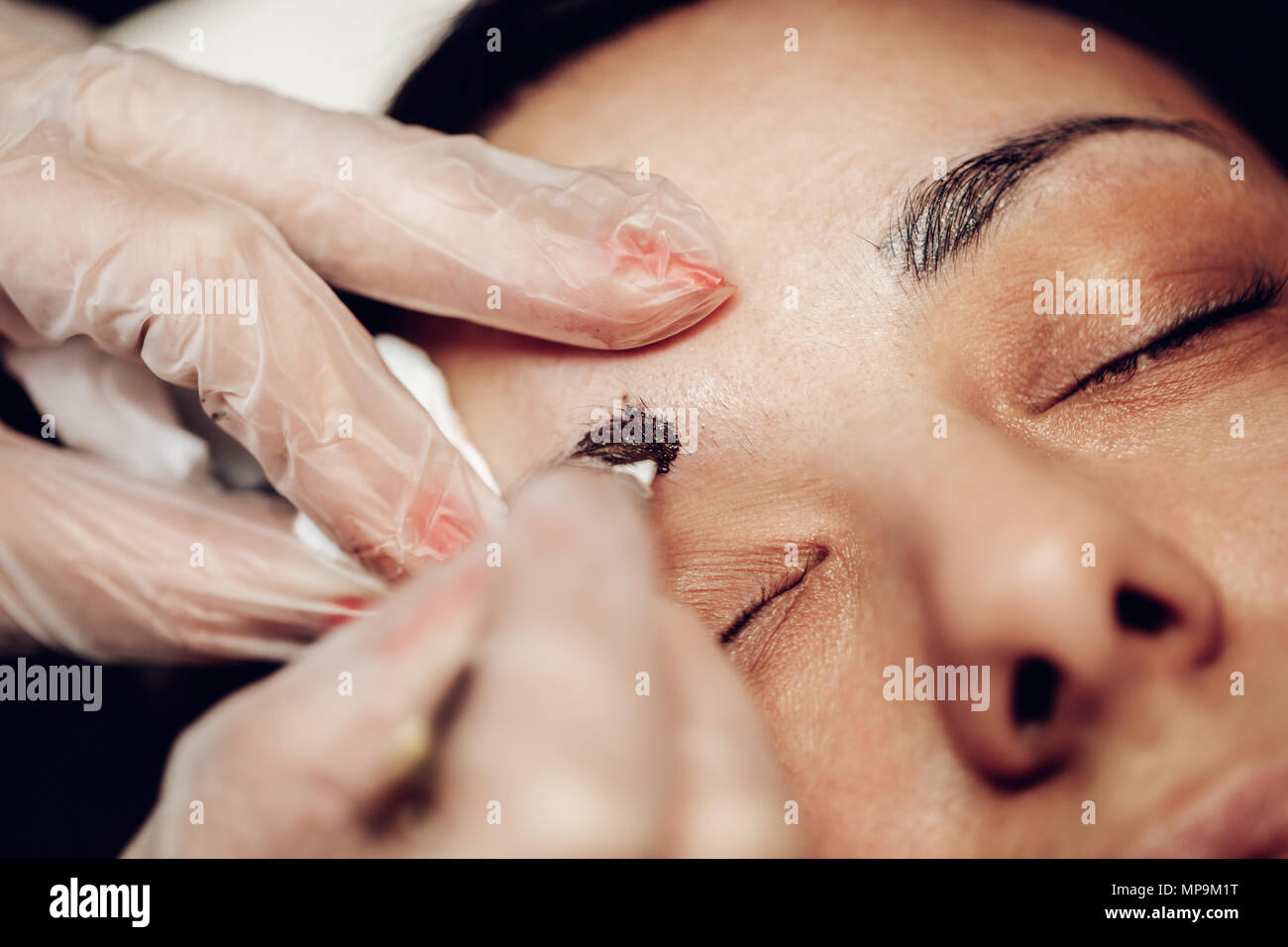 Close-up di una estetista mani microblading sopracciglia al modello. Foto Stock