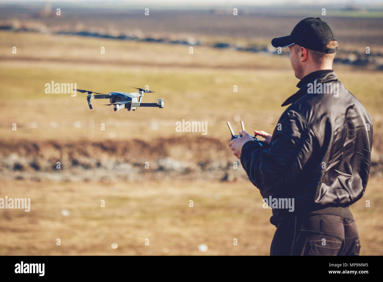 Giovane Azienda controller remoto nelle sue mani e a prendere foto aerea con piccole e compatte del drone. Messa a fuoco selettiva. Foto Stock