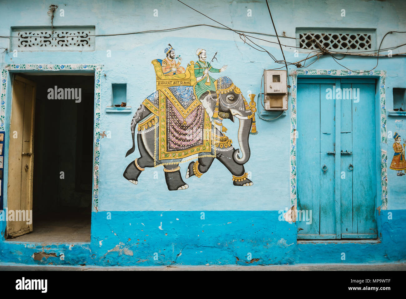 Una pittura colorata di un elefante su un teal blu nella parete tra portali in Udaipur, India Foto Stock