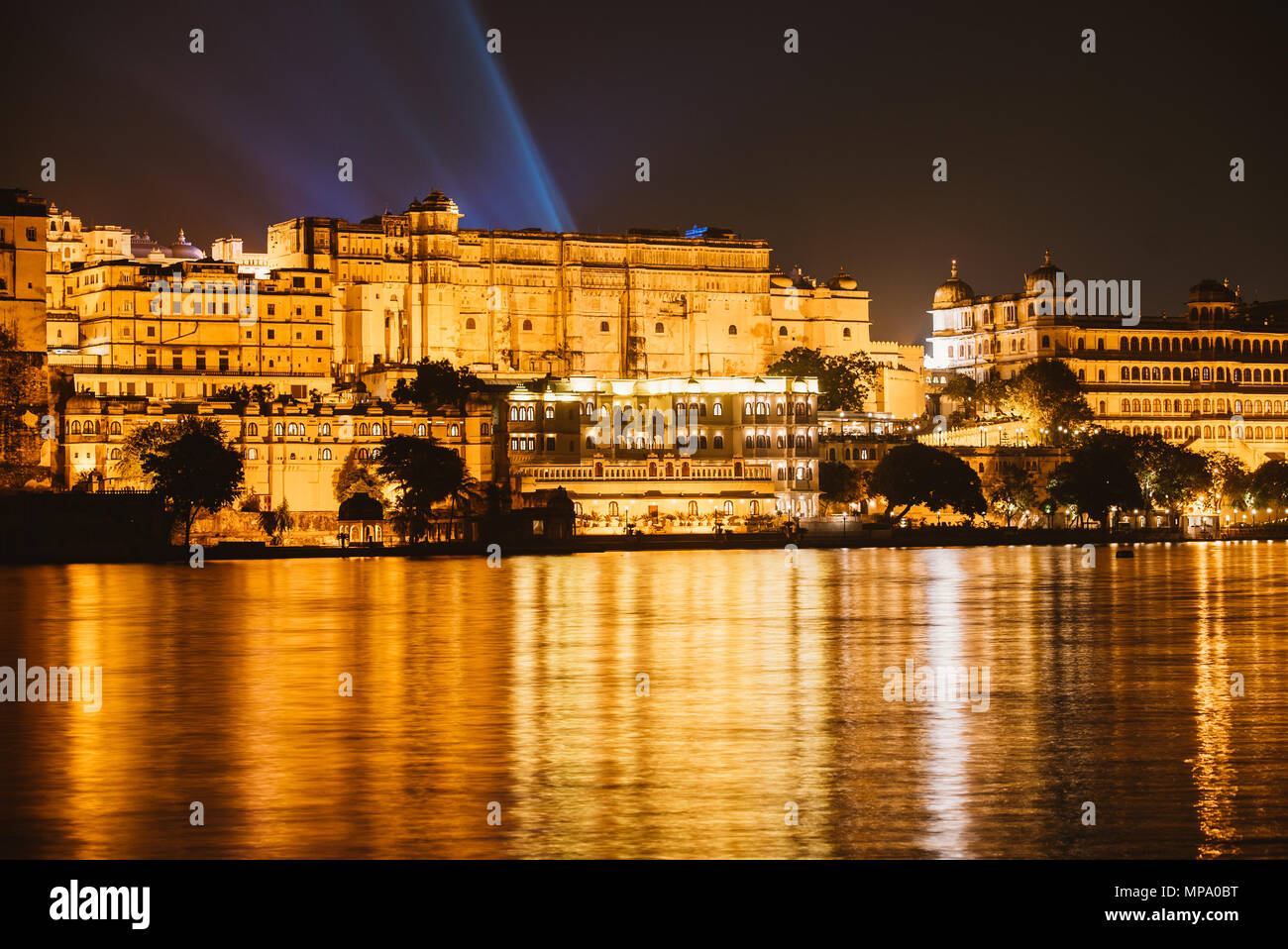 Vista sul palazzo di città di notte dall'acqua in Udaipur, India Foto Stock